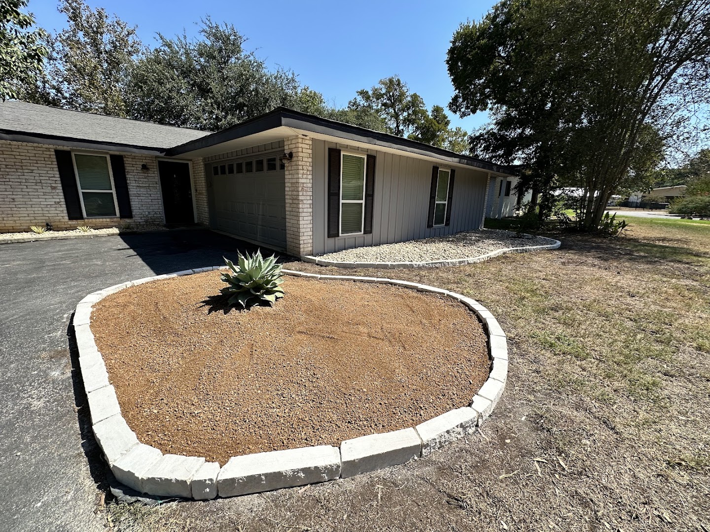 Curved rock landscape bed with concrete border, hill country TX