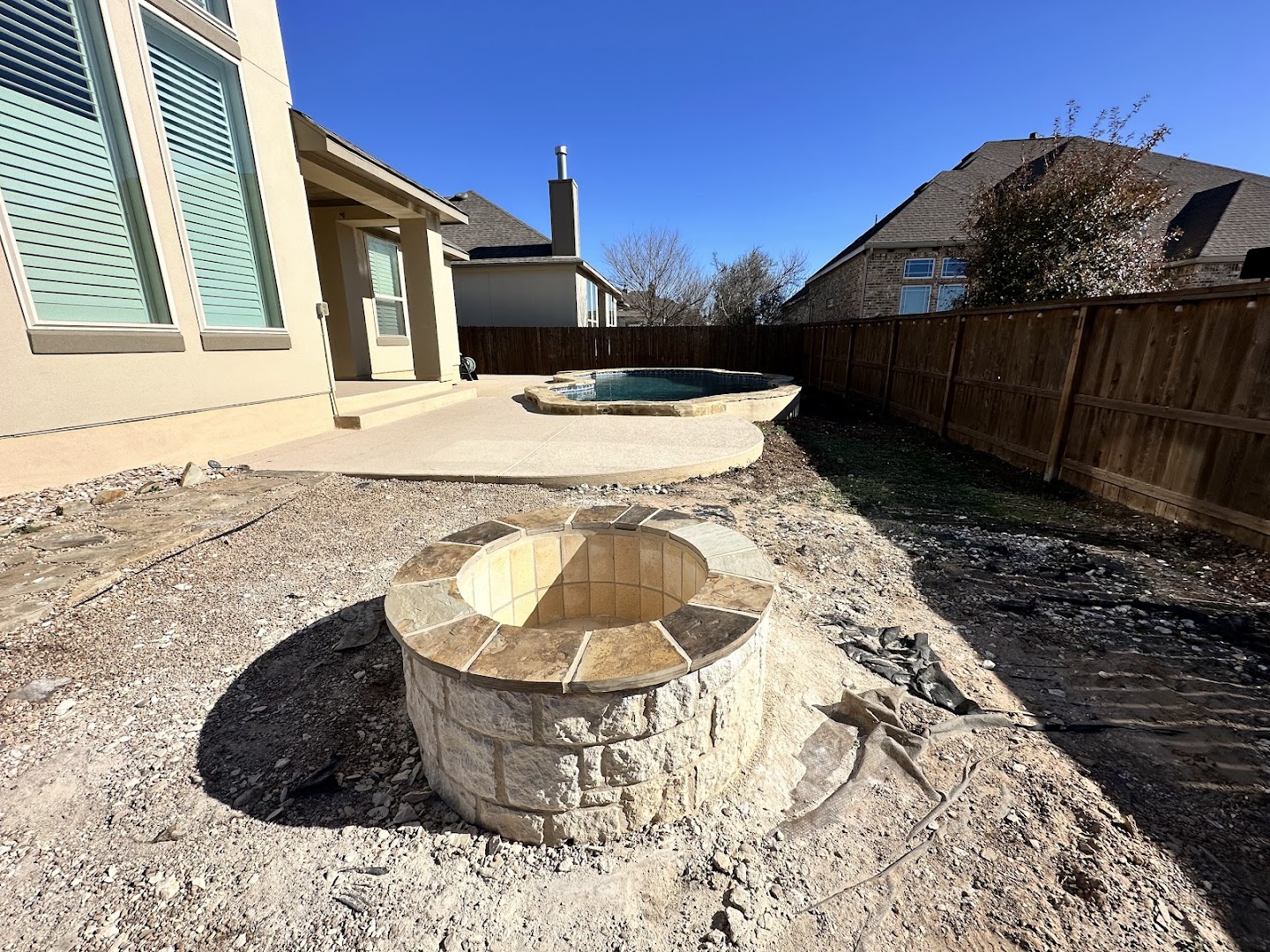Stone fire pit built into a landscaped yard, Seguin TX